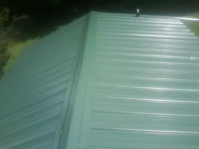 New green metal panels meeting at the ridge of a roof — Flat Roof Repair work by our crew in Sun City Center