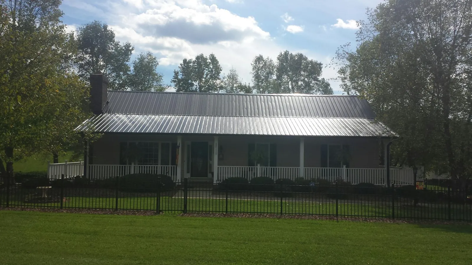 Gray metal roof on a brick ranch with a full width front porch — Gutter Guard Installation work by our crew in Sun City Center