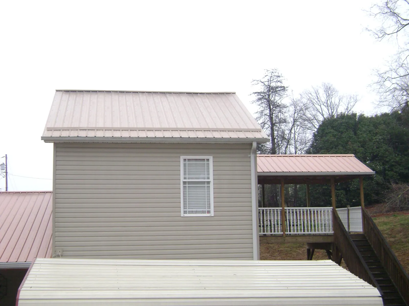 Tan metal roofs on a two story addition and attached porch, from a Roof Replacement job in Sun City Center