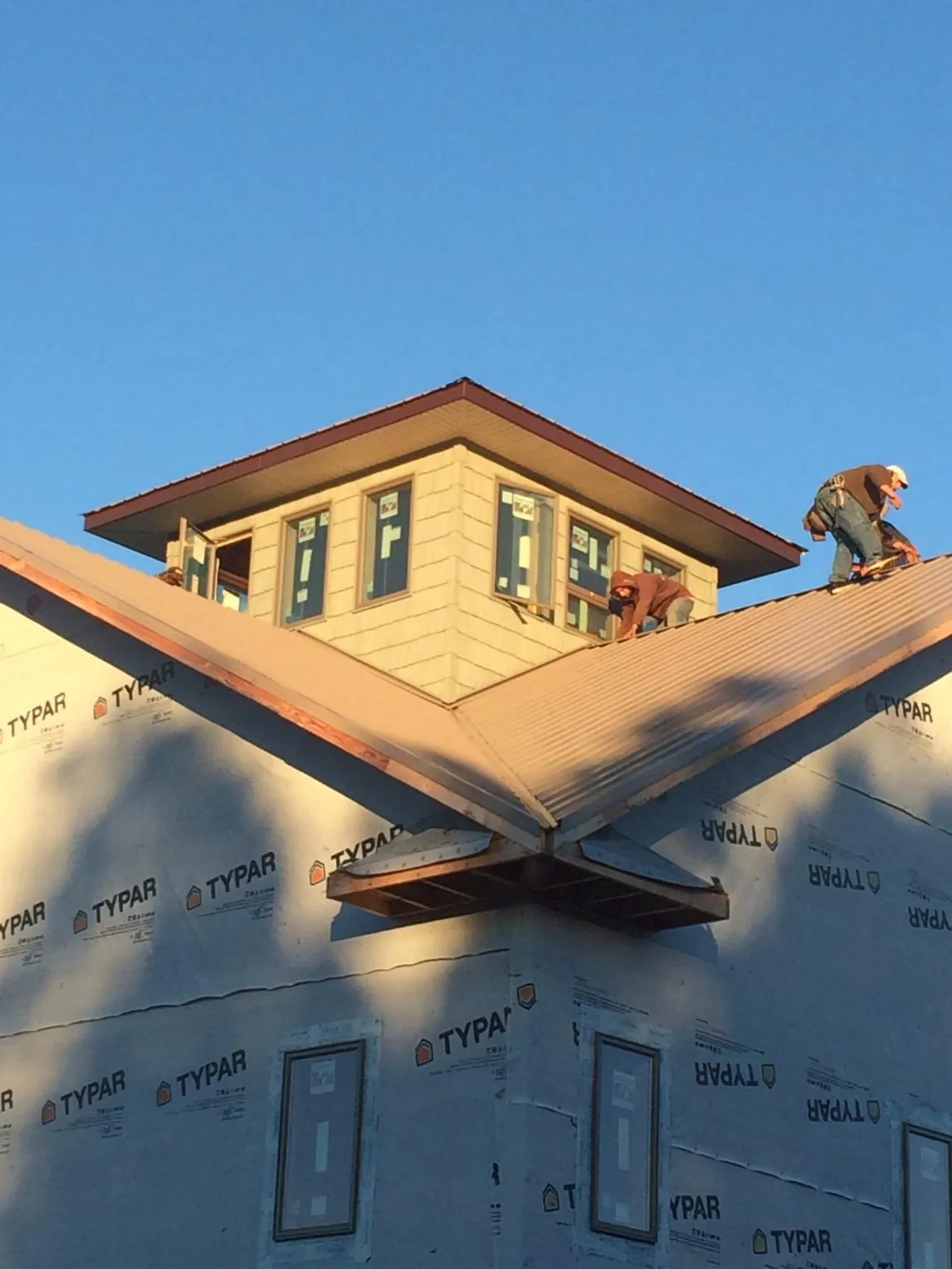 Roofers working around a rooftop cupola on a new metal roof at sunset — Roof Waterproofing in Sun City Center by Roofing Brothers